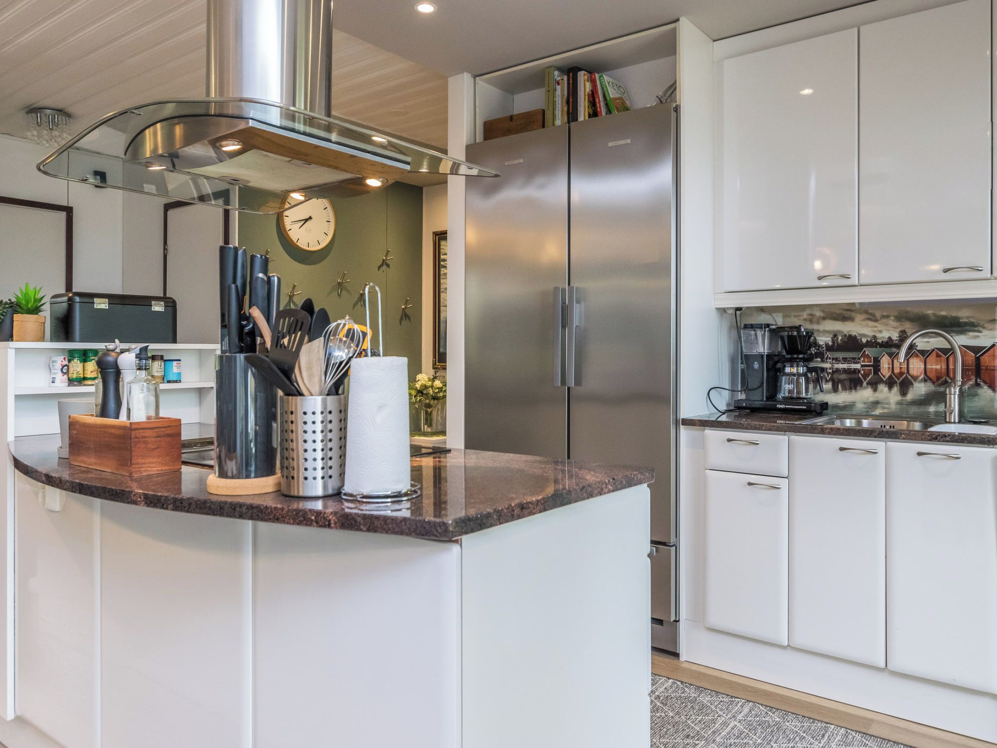 A modern kitchen with a stainless steel refrigerator, a built-in oven, and a coffee machine.
