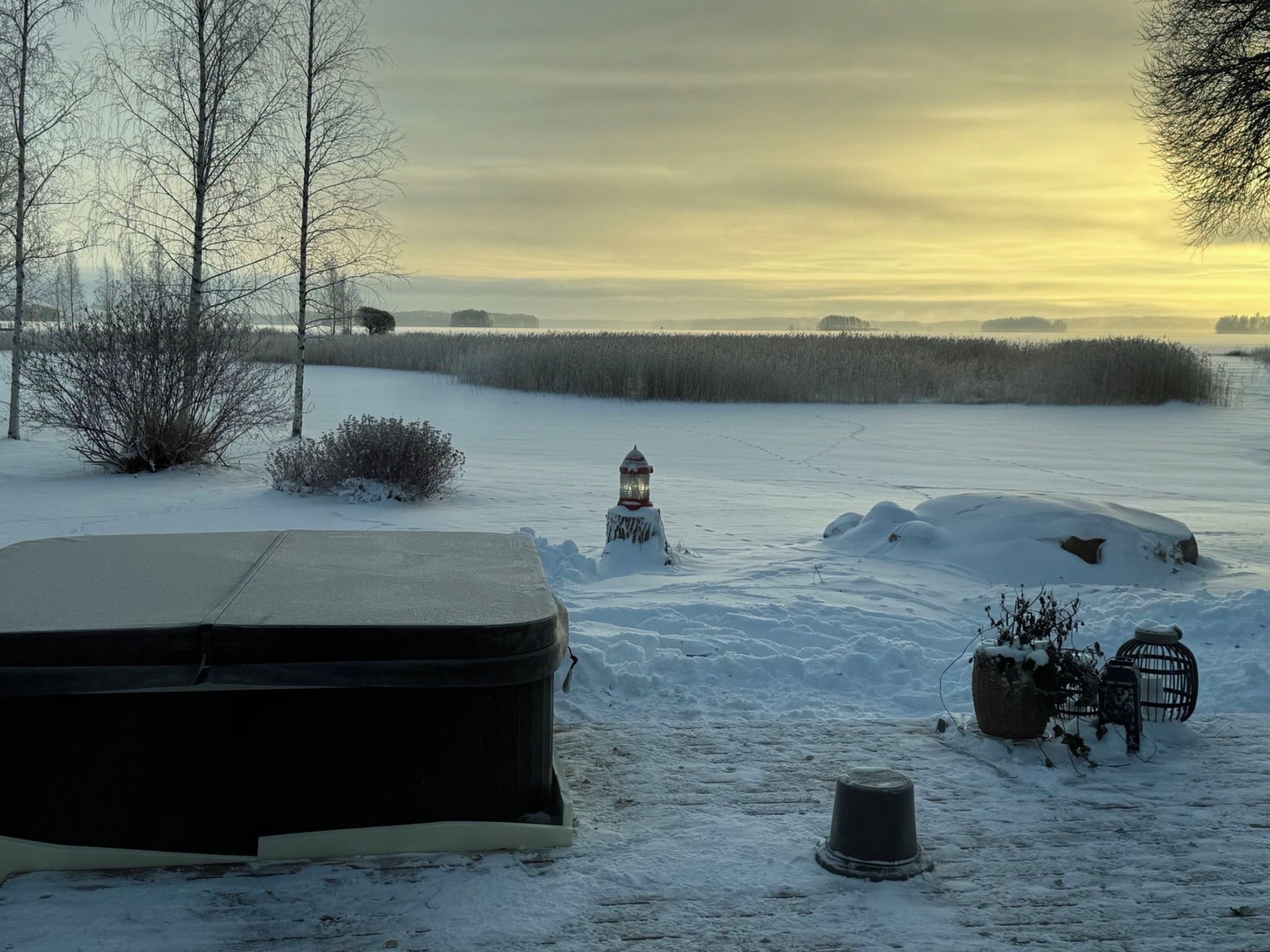 A snowy landscape with a snow-covered car, a lantern, and a birdcage.