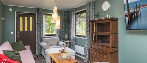 A room with a bed, a sofa, a chair, a wooden cabinet, and a window with curtains.