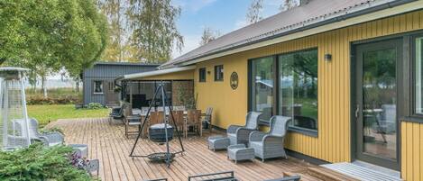 Eine moderne Außenterrasse mit Sitzgelegenheiten, Grill und überdachtem Bereich.