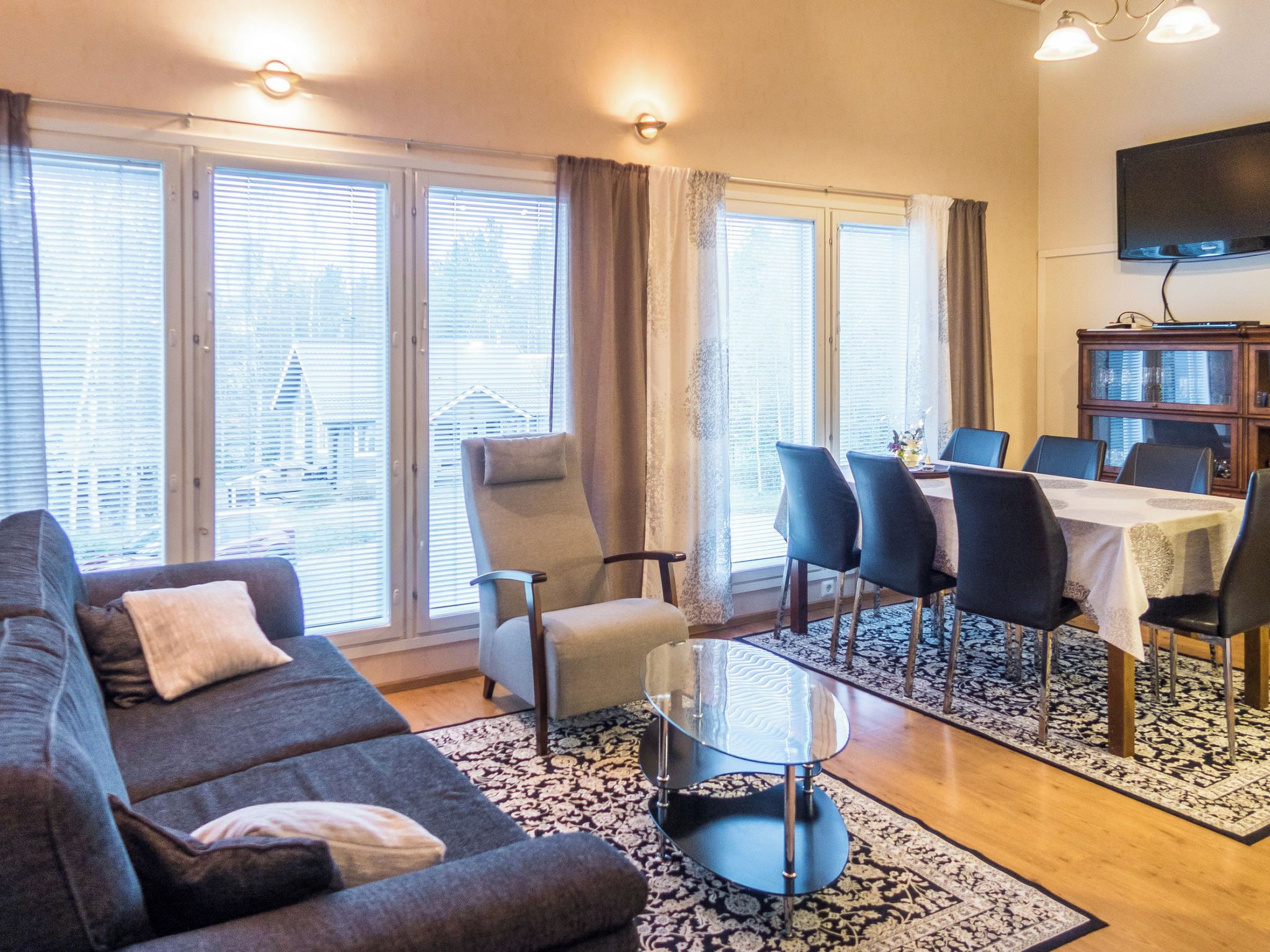 Un salon comprenant un canapé, des fauteuils, une table basse en verre et un coin repas avec une table et des chaises.
