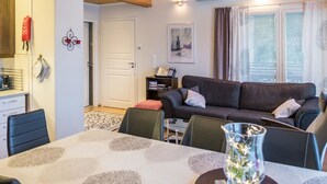 Een gezellige woonkamer met een bank, eettafel en een klok aan de muur.