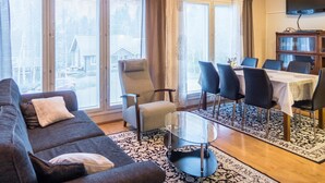 Een moderne woonkamer met een bank, een glazen salontafel en een eethoek met stoelen en een tafel.