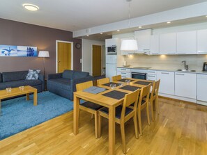 A modern apartment with a living area, a dining table, and a kitchenette.