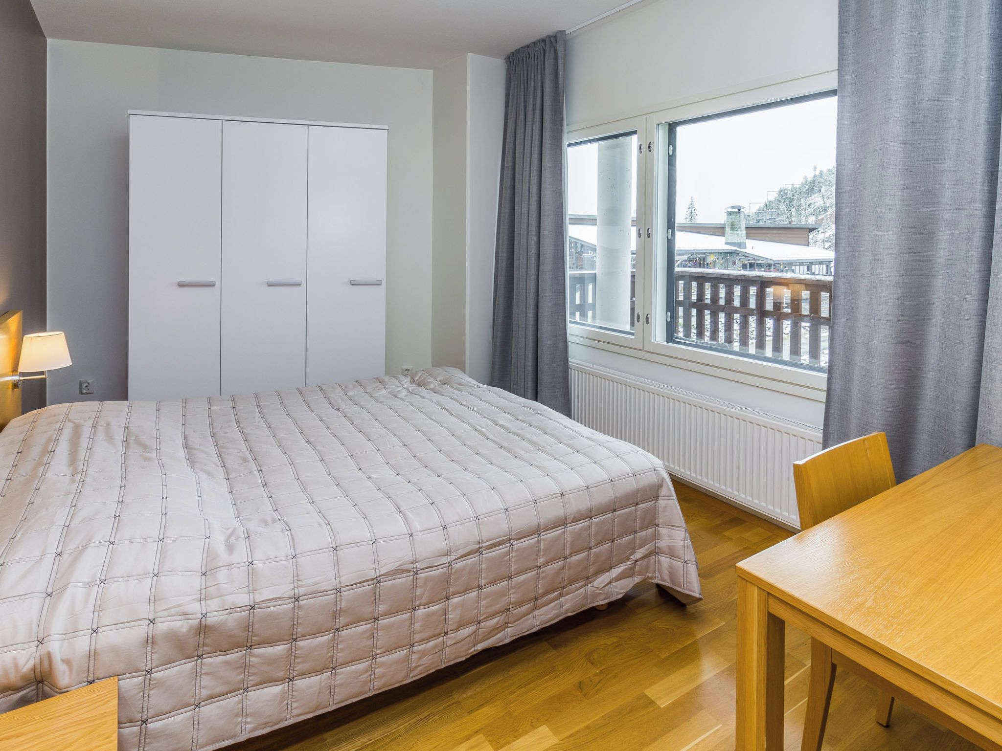 Een slaapkamer met een bed, een kledingkast, een raam met uitzicht en een tafel.
