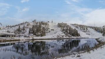 Lumipeitteinen maisema, jossa on järvi, puita ja hiihtohissi.