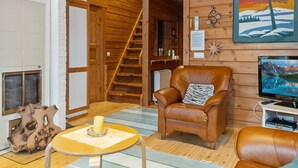A cozy room with a leather armchair, a television, and a wooden staircase.