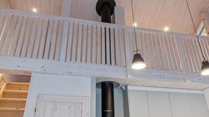 A modern interior with a wooden ceiling, a staircase, and pendant lighting.