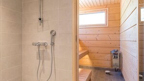 A wooden cabin bathroom with a shower, a toilet, and a bench.