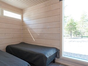 Een kamer met twee bedden, houten wanden en een groot raam.
