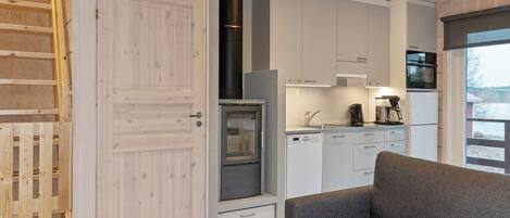 Eine moderne Küche mit weißen Schränken, einem Backofen und einer Kaffeemaschine.