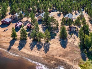 Zona residencial con varias casas rodeadas de árboles, una playa y un camino de tierra.