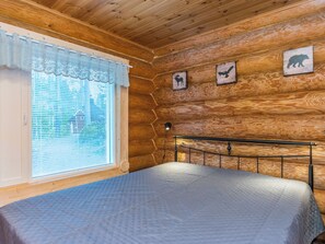 Une pièce de style cabane en bois, avec un lit, une fenêtre équipée de stores et trois silhouettes d’animaux fixées au mur.