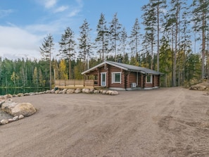 Une cabane avec une allée en terre, entourée d’une forêt.
