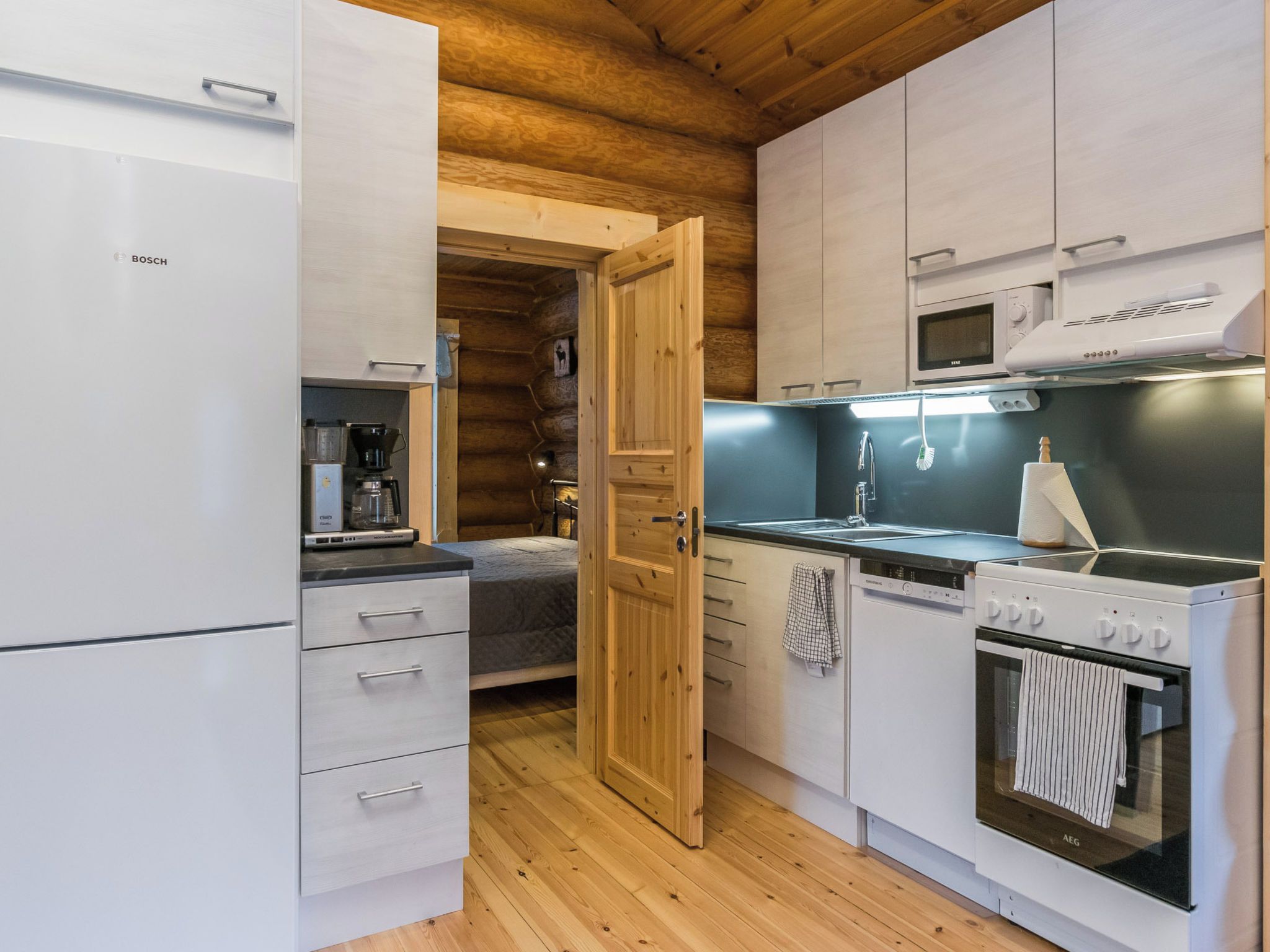 Eine kompakte Küche mit Kühlschrank, Mikrowelle, Herd und Kaffeemaschine.