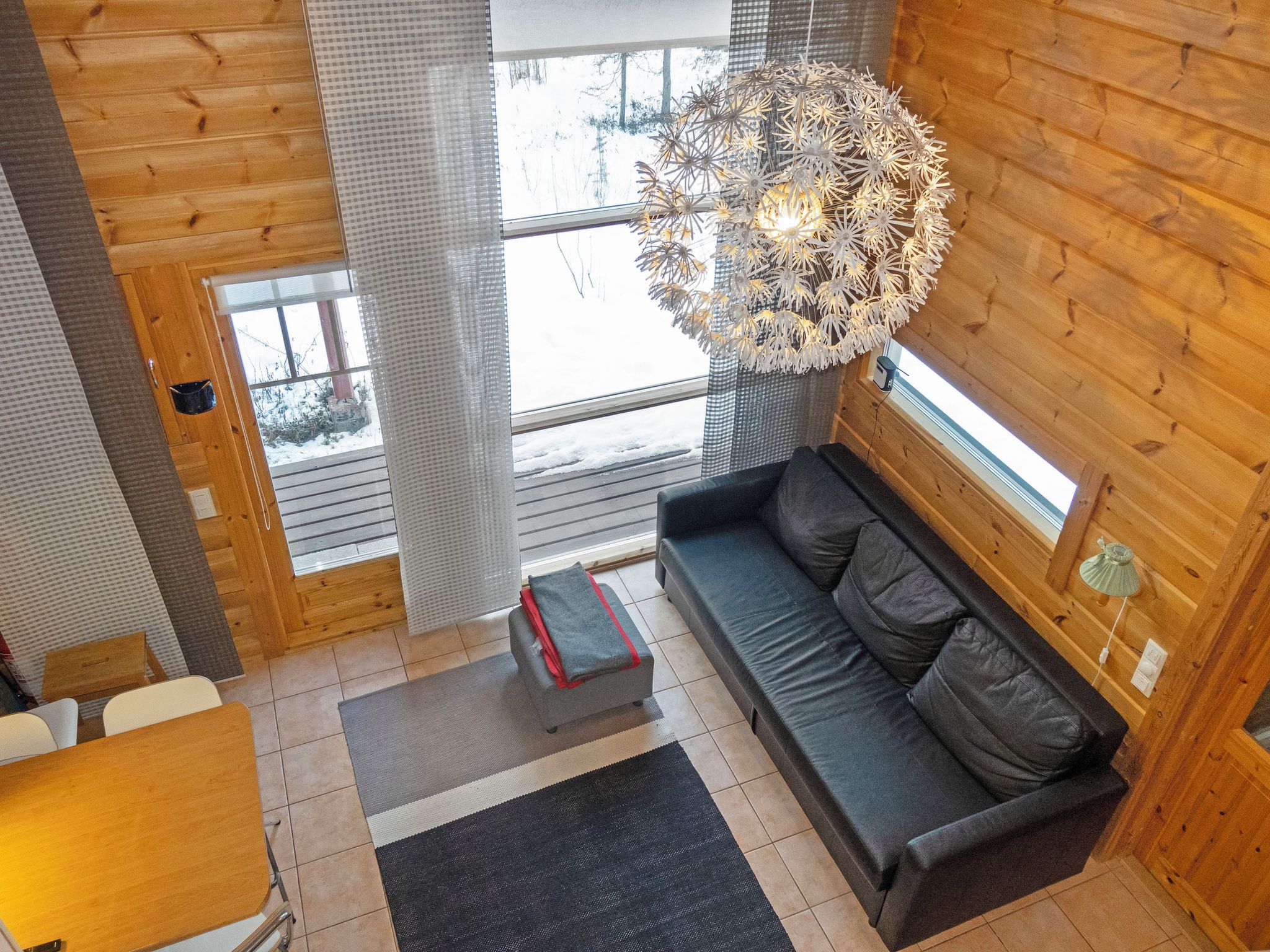 Ein modernes Interieur mit einem grauen Sofa, einer Holzbalkendecke und einem großen Fenster.