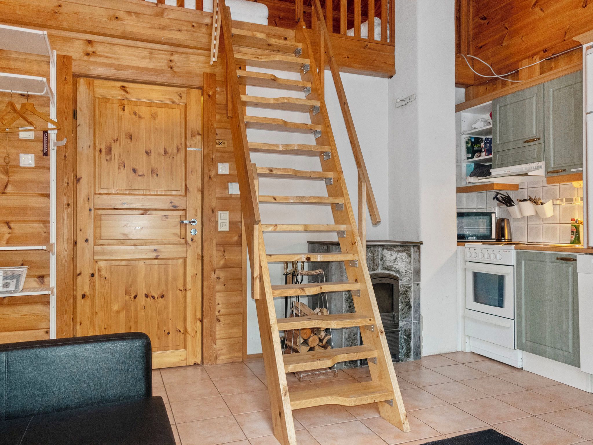Eine Holztreppe führt zu einer oberen Ebene, eine Küche mit modernen Geräten und ein Kamin.