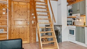 A wooden interior with a wooden staircase, a fireplace, and a kitchen area. - Aisakello by Interhome (Kittilä)