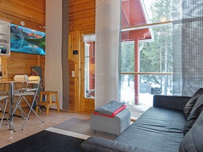 A cozy cabin interior with a sofa, a small table, and a television mounted on the wall. - Aisakello by Interhome (Kittilä)