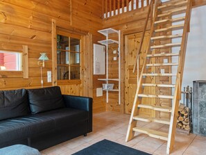 A wooden interior with a black sofa, a ladder, and a fireplace. - Aisakello by Interhome (Kittilä)