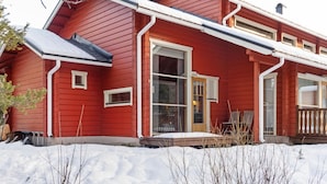A red wooden house with a sloped roof, white trim, and a front porch with a bench. - Aisakello by Interhome (Kittilä)