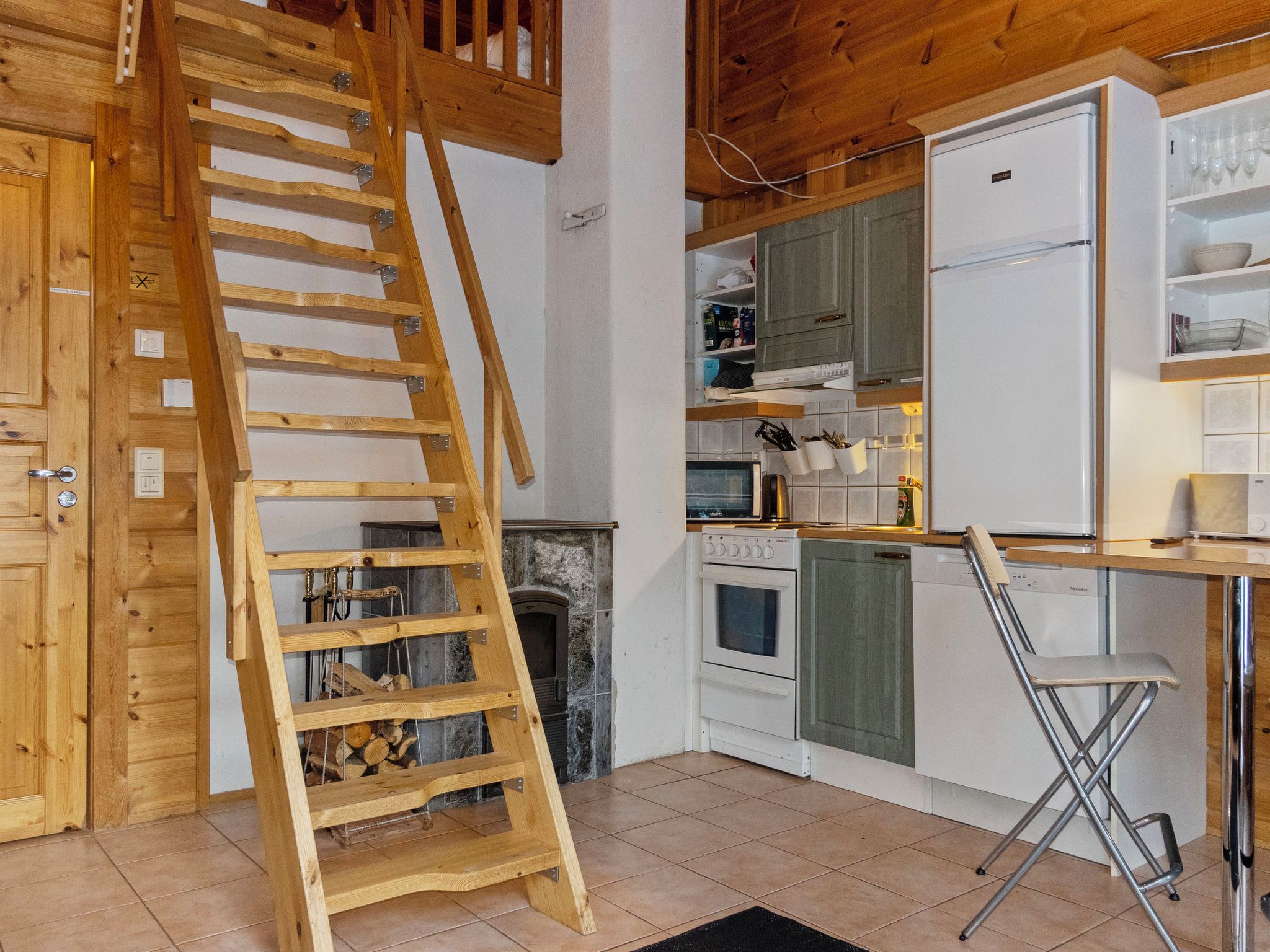 Eine Küche mit einer Holztreppe zu einem Schlafzimmerboden, einem Kamin und modernen Geräten.