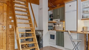 A kitchen with wooden cabinets, a white refrigerator, a stove, and a wooden ladder. - Aisakello by Interhome (Kittilä)