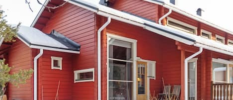 Een rode woning met een groot voorraam, schoorsteen en een sneeuwbedekt dak.