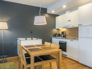 A modern kitchen with white cabinets, a wooden dining table, and a coffee machine. - Levi chalets 1602 by Interhome (Kittilä)