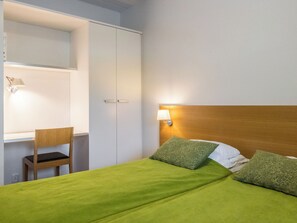 A hotel room with a bed, a desk, and a chair.