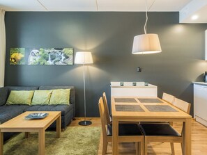 A modern living room with a sofa, coffee table, and dining table. There is a kitchen area with a counter and appliances. - Levi chalets 1602 by Interhome (Kittilä)