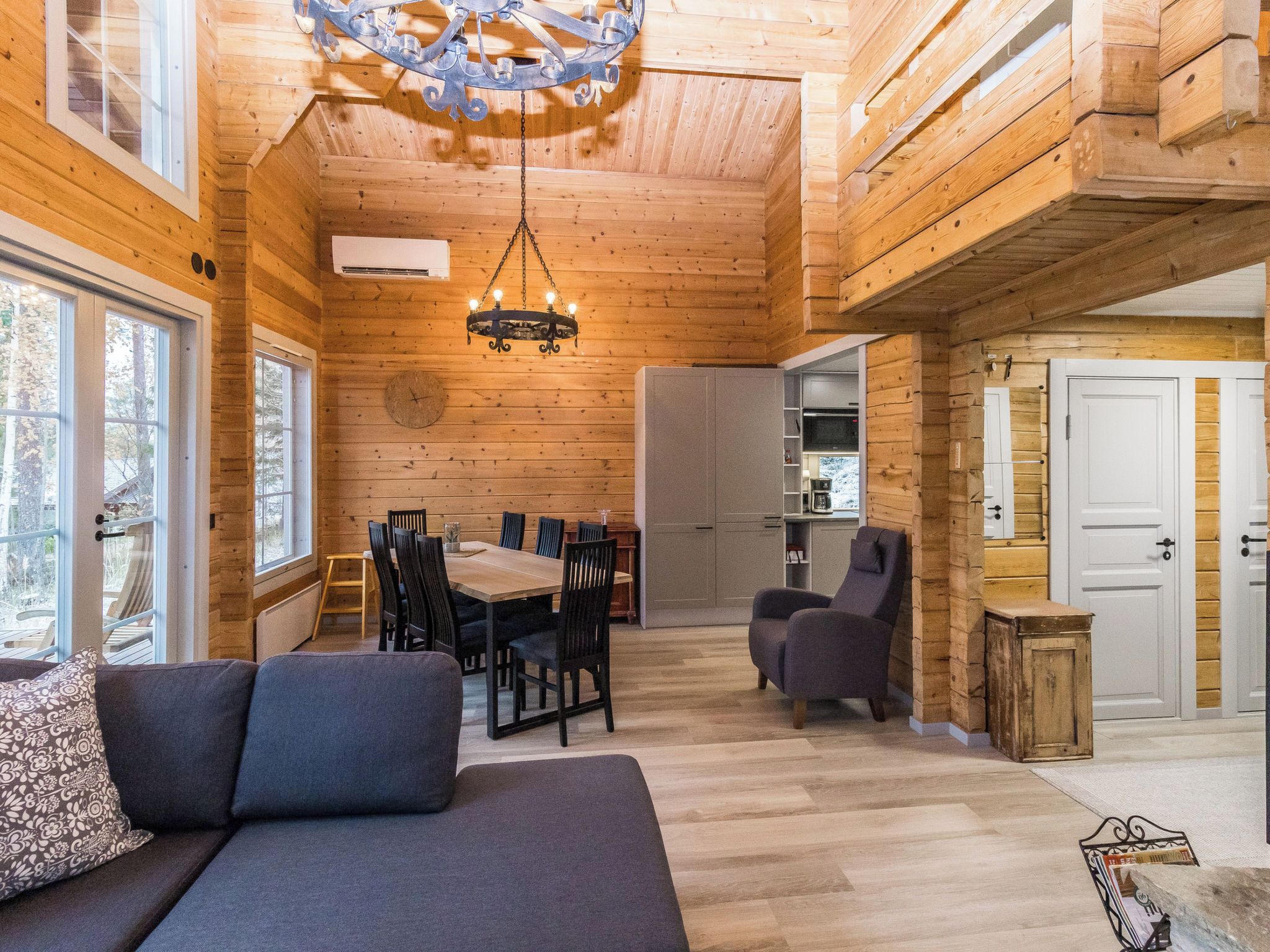 A cozy cabin interior with a dining area, a sofa, and a chair.