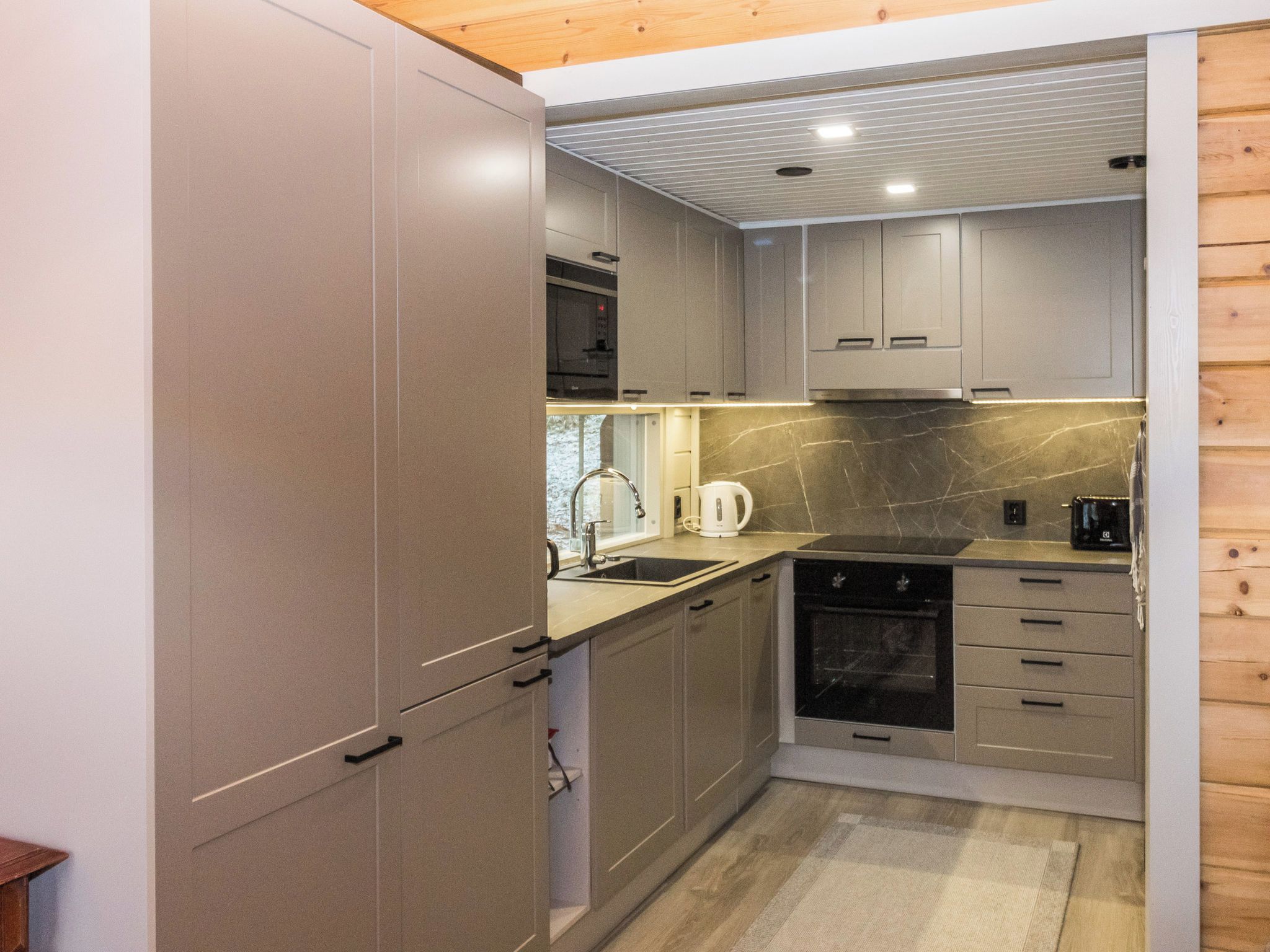Une cuisine compacte dotée d’appareils électroménagers intégrés, d’un évier et d’une cuisinière.