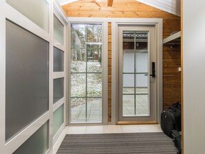 Un interno moderno con una porta scorrevole in vetro che dà su uno spazio esterno, una panca e un appendiabiti.
