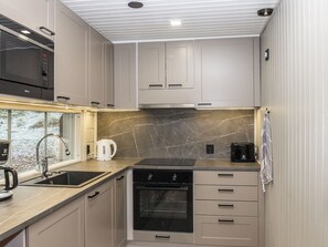 Una cucina compatta con forno a microonde, bollitore, tostapane e forno.