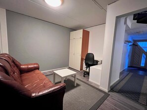 A room with a leather sofa, a small white table, a black office chair, and a white cabinet. - Jytilevi b by Interhome (Kittilä)