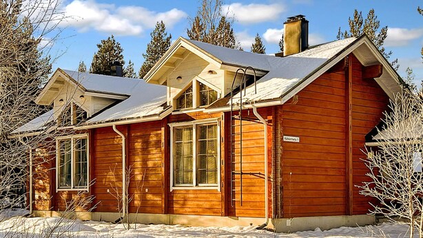 Une cabane en bois avec un toit en pente, de grandes fenêtres et une cheminée.