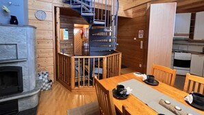Un intérieur en bois avec un escalier en colimaçon, une cheminée et un coin repas comprenant des chaises et une table.