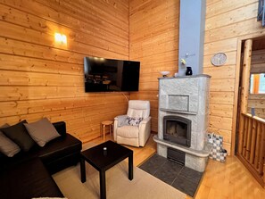 A cozy room with a fireplace, a sofa, a television, and a small table. - Jytilevi b by Interhome (Kittilä)