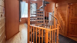 Un intérieur en bois avec un escalier en colimaçon, une fenêtre avec des rideaux et une porte.
