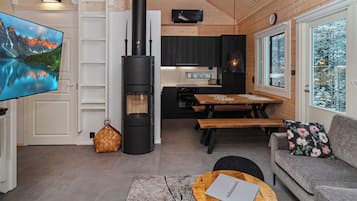 A cozy cabin interior with a fireplace, a television, a dining area, and a sofa.