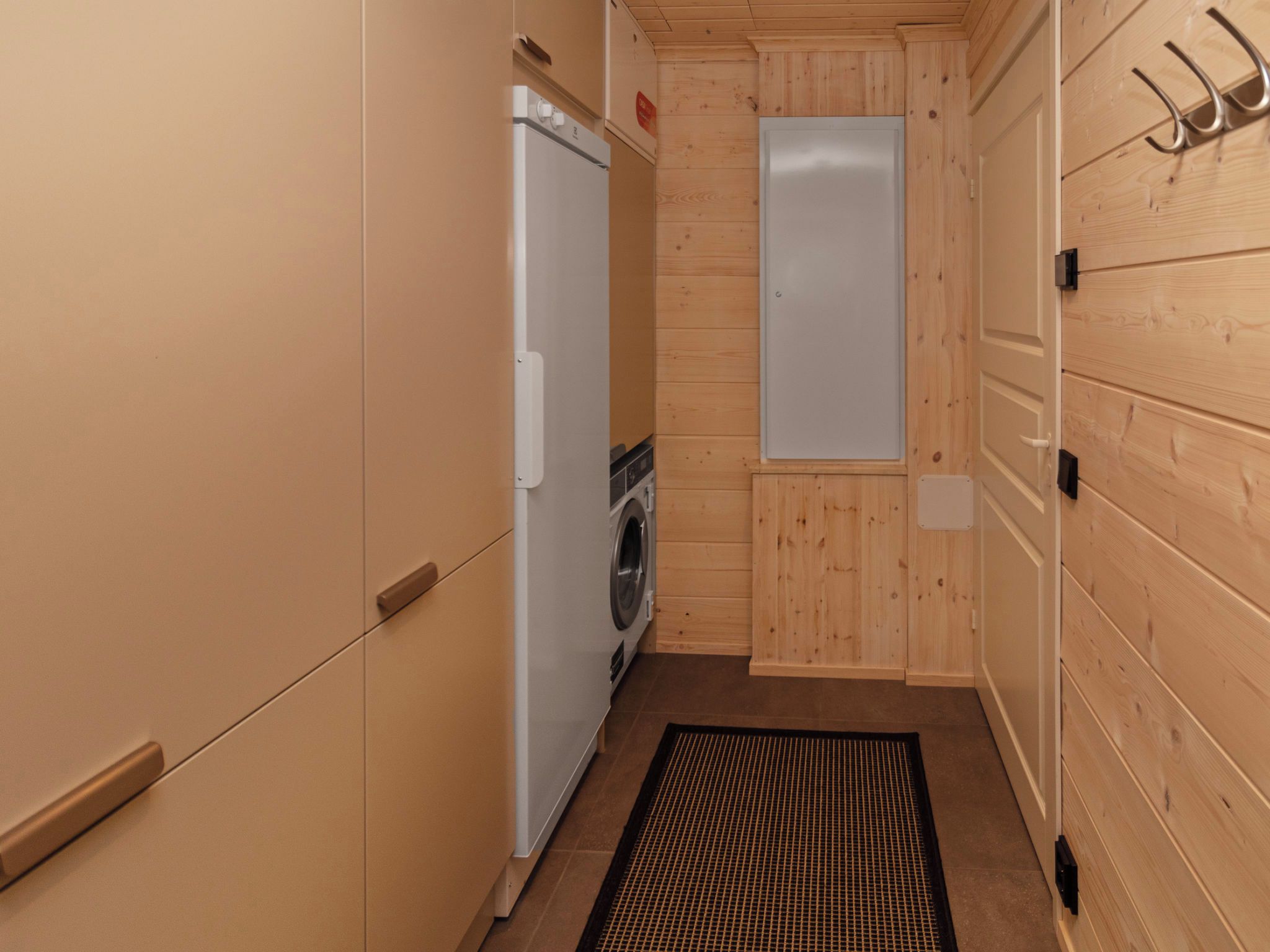 A compact laundry room with a washing machine, a dryer, and a door with a metal hook.