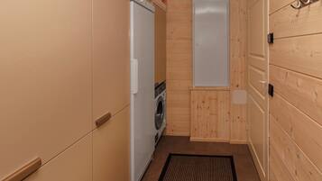 A compact laundry room with a washing machine, a dryer, and a door with a metal hook.
