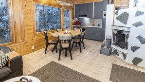 Een gezellig chalet interieur met een houten eethoek, keuken en een open haard.
