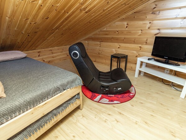 A room with a bed, a massage chair, a television, and a small table.