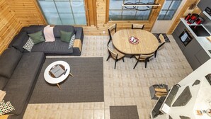 Een modern ingerichte blokhut met een bank, ronde eettafel en keukenhoek.