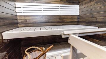Un sauna avec un banc et un seau en bois.