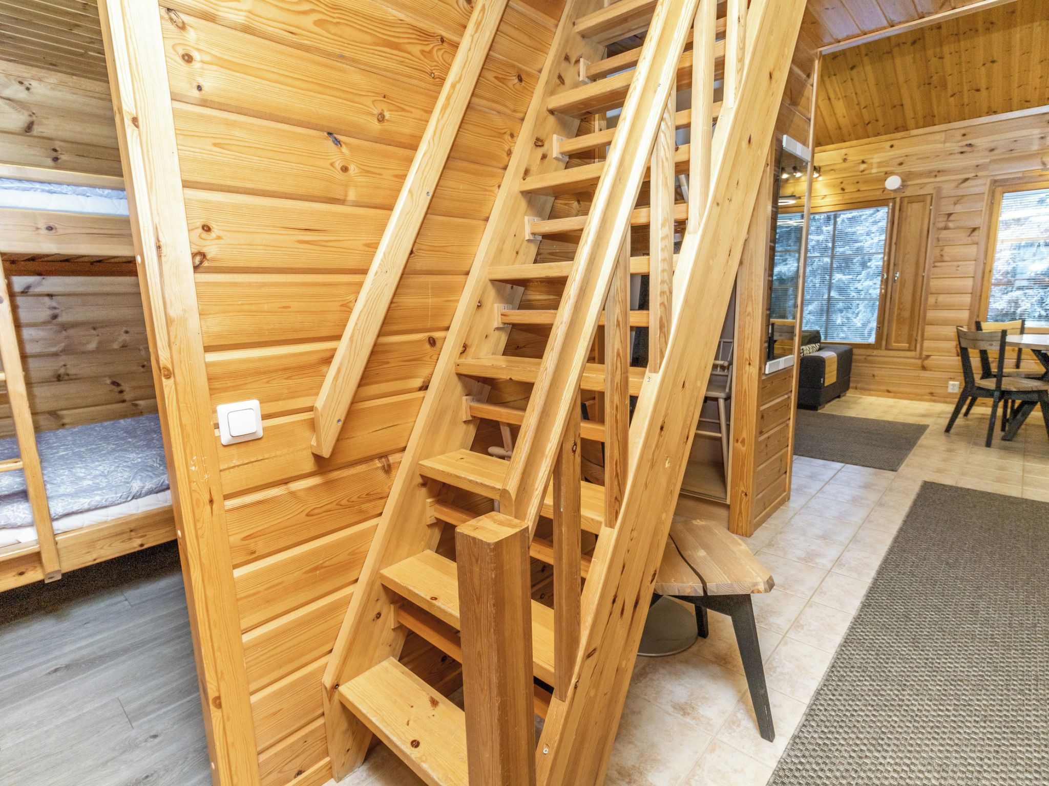 Un interior de madera con una escalera de madera, una cama y un comedor.
