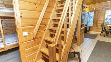 Un intérieur en bois avec un escalier en bois, un lit et un coin repas.