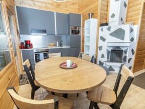 A compact kitchen with modern appliances, a dining table with chairs, and a stone fireplace.